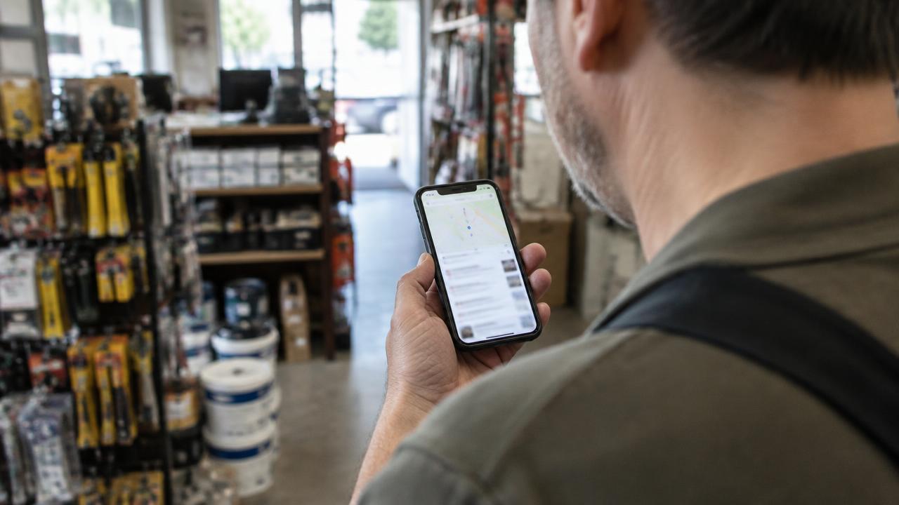 Commerçant consultant une carte de recherche locale sur son téléphone dans sa quincaillerie